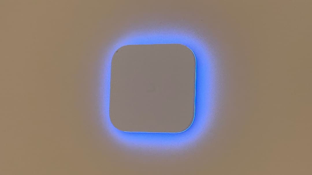 Close up of a UniFi access point or security device showing a glowing blue square LED border