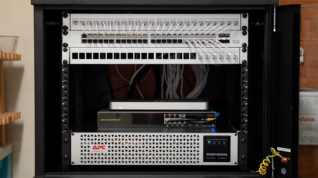 Close-up of a new Ubiquiti managed switch, patch panels, and APC UPS installed in a server rack.