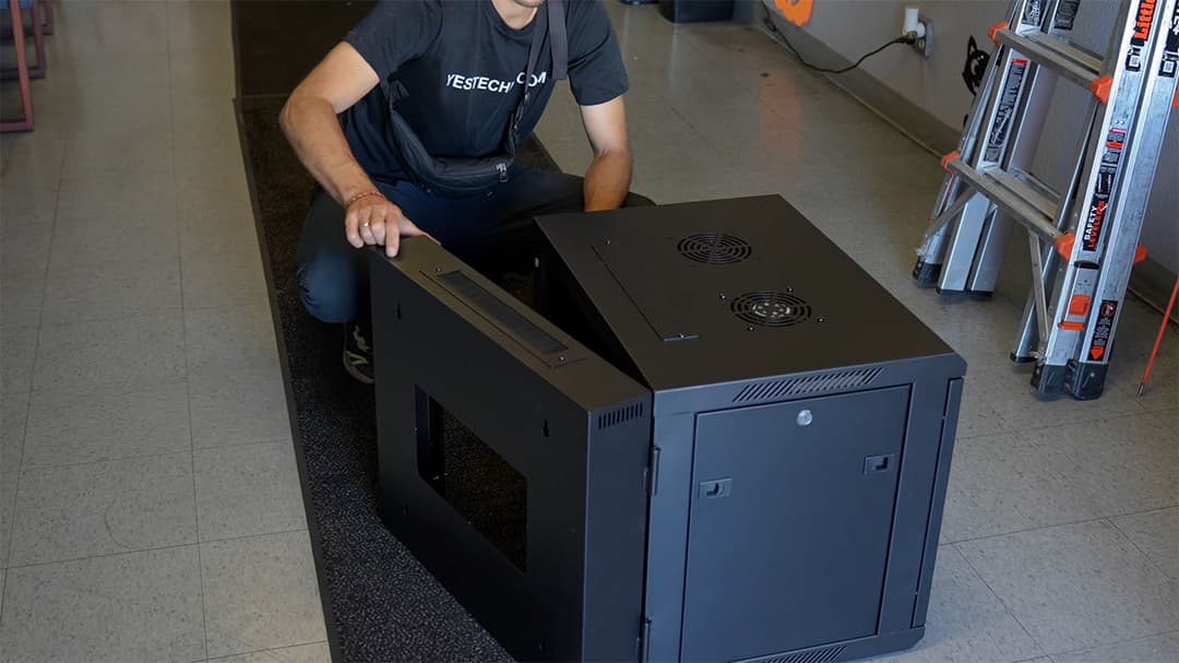 IT technicians bringing a new nine-unit network cabinet into the server room.