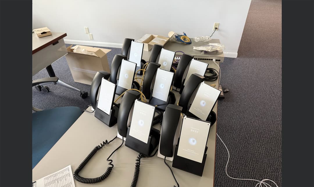 Multiple UniFi Talk IP phones undergoing mass provisioning, firmware updates, and network validation prior to corporate deployment.